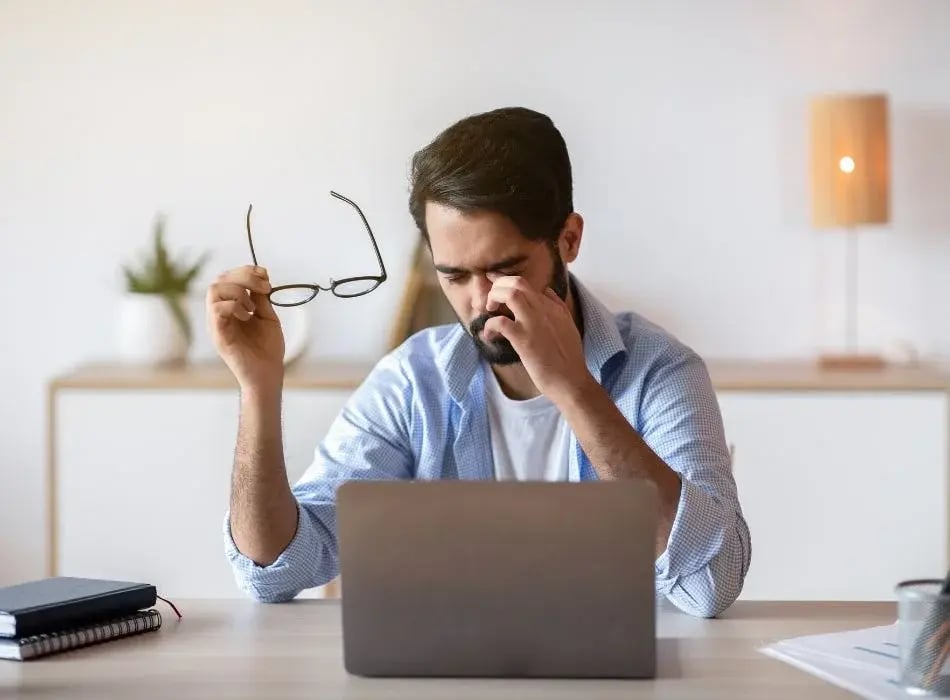 man with glasses rubbing eyes