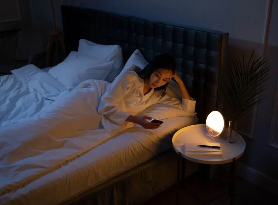 woman looking at phone in bed